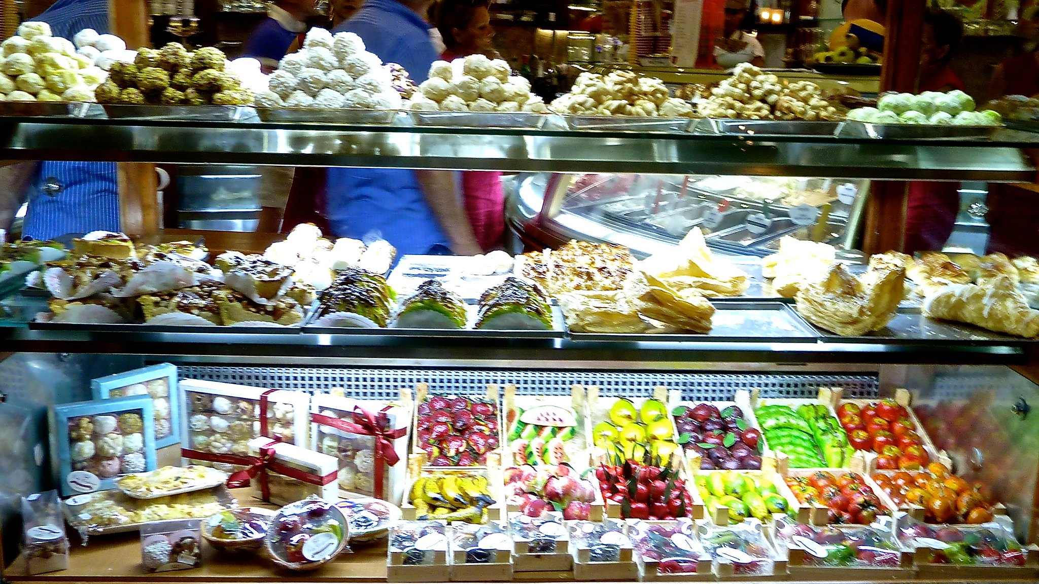 Vetrina di una pasticceria siciliana con cassette di frutta martorana colorata e altri dolci di mandorla